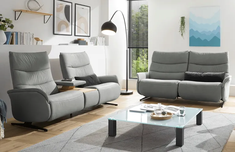 Modernes Wohnzimmer mit grauen Relaxsesseln und Sofa, stilvoll eingerichtet mit Glas-Couchtisch.